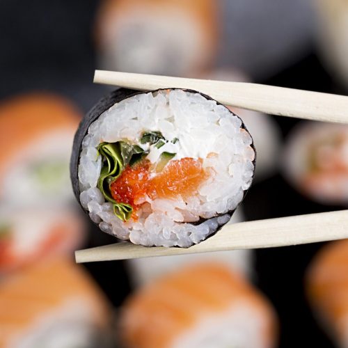 close-up-chopsticks-with-sushi-roll
